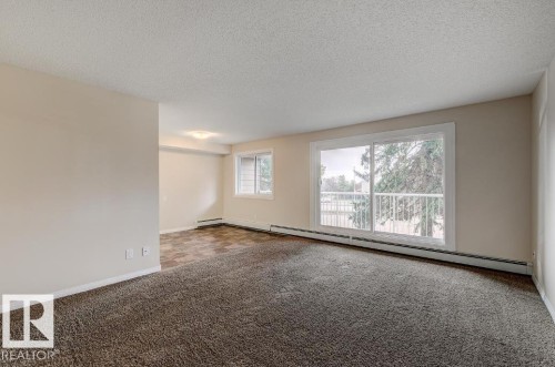 Spacious living area featuring a large sliding glass door opening to an outdoor balcony - 5425 144B Avenue Northwest, Edmonton, AB - Indoor Photo Showing Other Room