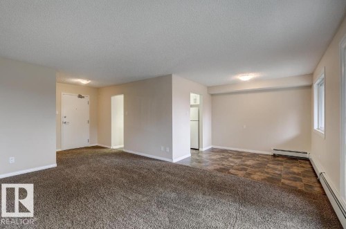 Spacious room featuring neutral paint, textured ceiling, brown carpet flooring, and a window with a radiator - 5425 144B Avenue Northwest, Edmonton, AB - Indoor Photo Showing Other Room
