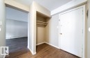 Entryway featuring wood-finish flooring, a built-in closet with shelving, a white entry door, neutral wall paint, and white trim - 3312 105 Avenue Northwest, Edmonton, AB  - Indoor Photo Showing Other Room 