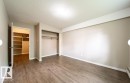 Neutral-toned room featuring wood-finish flooring, white baseboards, and a built-in closet with shelving and hanging rods - 3312 105 Avenue Northwest, Edmonton, AB  - Indoor Photo Showing Other Room 