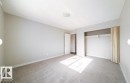 Spacious room featuring neutral carpeting, light gray wall paint, and a built-in closet with a hanging rod and shelf - 3312 105 Avenue Northwest, Edmonton, AB  - Indoor Photo Showing Other Room 