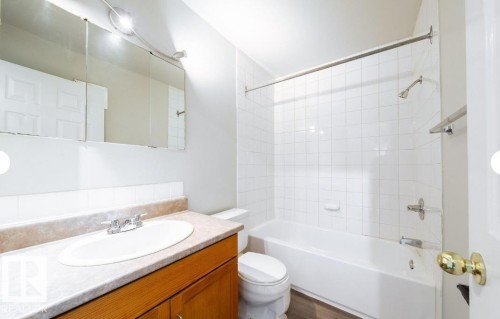 Bathroom featuring a single vanity with a laminate countertop, integrated sink, and wood-finish cabinetry - 3312 105 Avenue Northwest, Edmonton, AB - Indoor Photo Showing Bathroom