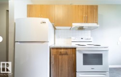 Kitchen area featuring wood-finish cabinetry, white appliances, a white tile backsplash, and a light-toned countertop - 