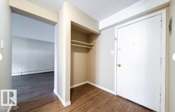 Entryway featuring wood-finish flooring, a built-in coat closet with shelving, and a clean white entry door - 