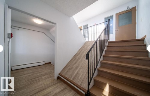 Stairwell featuring wood-finish treads, black metal railing, and a sloped wood-finish floor section - 3312 105 Avenue Northwest, Edmonton, AB - Indoor Photo Showing Other Room