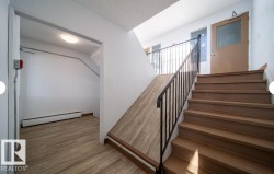 Stairwell featuring wood-finish treads, black metal railing, and a sloped wood-finish floor section - 