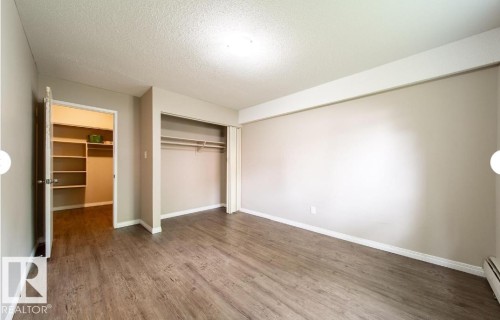 Spacious room featuring wood-finish flooring, neutral wall tones, and white baseboards - 3312 105 Avenue Northwest, Edmonton, AB - Indoor Photo Showing Other Room