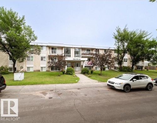 Three-story stucco and siding building with multiple balconies, a central entrance, and a manicured front lawn - 3312 105 Avenue Northwest, Edmonton, AB - Outdoor