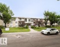 Three-story stucco and siding building with multiple balconies, a central entrance, and a manicured front lawn - 3312 105 Avenue Northwest, Edmonton, AB  - Outdoor 