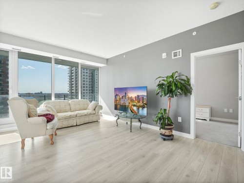 Expansive living space featuring light wood-finish flooring, a wall of large windows, and a neutral color palette - #1501 10180 103 St Nw, Edmonton, AB - Indoor Photo Showing Living Room
