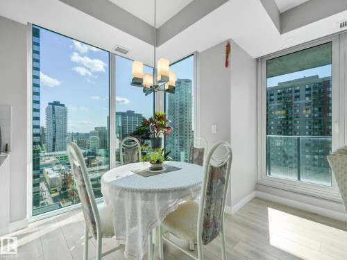 Floor-to-ceiling windows with city surroundings, complemented by light wood-finish flooring and a contemporary pendant light fixture - #1501 10180 103 St Nw, Edmonton, AB - Indoor Photo Showing Dining Room