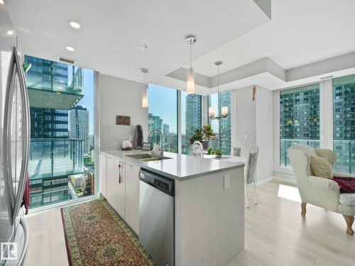 Open-concept kitchen featuring an integrated island, stainless steel appliances, and large windows - #1501 10180 103 St Nw, Edmonton, AB - Indoor Photo Showing Kitchen With Upgraded Kitchen