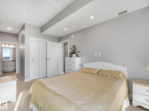 Neutral-toned bedroom featuring recessed lighting, a sliding closet door, and carpet flooring - #1501 10180 103 St Nw, Edmonton, AB - Indoor Photo Showing Bedroom