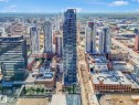 Modern high-rise residential building with a sleek glass facade, prominently situated amidst a dense urban landscape of diverse architectural styles - #1501 10180 103 St Nw, Edmonton, AB  - Outdoor With View 