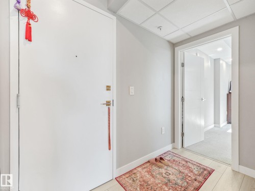 Entryway featuring light wood-finish flooring, light gray wall tones, and a bright white door with brass hardware - #1501 10180 103 St Nw, Edmonton, AB - Indoor Photo Showing Other Room