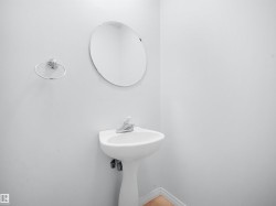 Pedestal sink with chrome faucet, circular wall mirror, and chrome towel ring - 