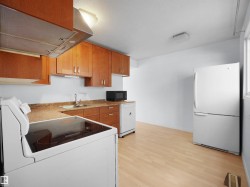 Kitchen with wood-finish flooring, light wood cabinetry, and white appliances including a range, refrigerator, dishwasher, and microwave - 