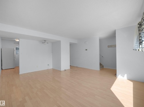 Spacious interior featuring light wood-finish flooring, white painted walls, and a semi-flush mount ceiling fixture - 10446 55 Avenue Nw, Edmonton, AB - Indoor Photo Showing Other Room