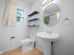 Pedestal sink with chrome faucet, oval mirror, and wall-mounted light fixture - 