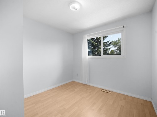 Bright room featuring light wood-finish flooring, white baseboards, and a large window with white trim - 10446 55 Avenue Nw, Edmonton, AB - Indoor Photo Showing Other Room