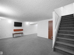 Spacious lower level featuring carpet flooring, white painted walls, and textured ceiling - 