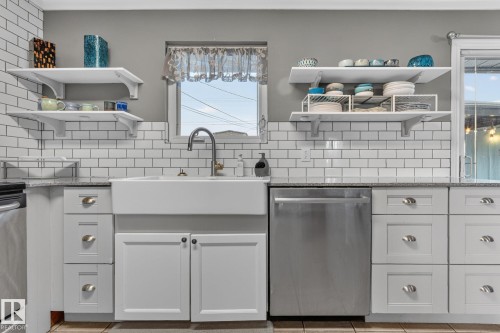 Kitchen featuring a white farmhouse sink with a gooseneck faucet, light gray cabinetry with varied drawer and door configurations, white subway tile backsplash, and granite-style countertops - 5307 104 Avenue Nw, Edmonton, AB - Indoor Photo Showing Kitchen With Upgraded Kitchen