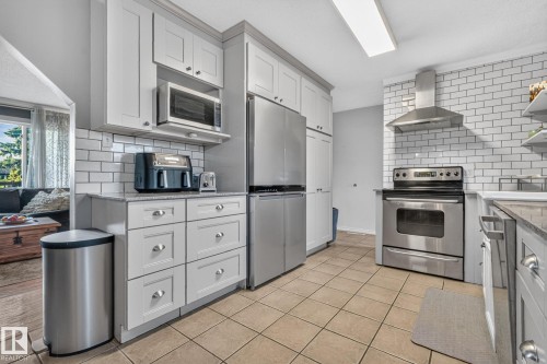 Kitchen featuring stainless steel appliances, grey shaker-style cabinetry, a white subway tile backsplash, and neutral tile flooring - 5307 104 Avenue Nw, Edmonton, AB - Indoor Photo Showing Kitchen With Upgraded Kitchen