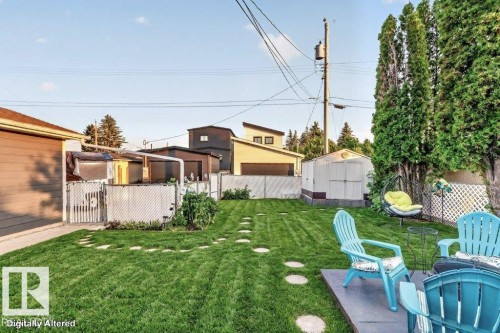 Expansive fenced backyard featuring a manicured lawn, stone paver pathway, and mature privacy trees - 5307 104 Avenue Nw, Edmonton, AB - Outdoor