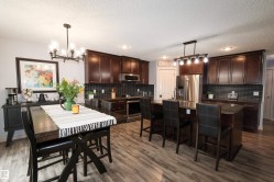 Kitchen and dining area featuring wood-finish flooring, dark wood cabinetry, and stainless steel appliances - 