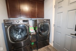 Laundry area featuring overhead cabinetry, tile flooring, and a paneled interior door with dark hardware - 