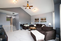 Spacious living area featuring a vaulted ceiling with a ceiling fan, track lighting, and soft gray wall finishes - 