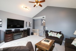Vaulted ceiling living room featuring an entertainment console with an electric fireplace, wood-finish ceiling fan, recessed lighting, and carpet flooring - 