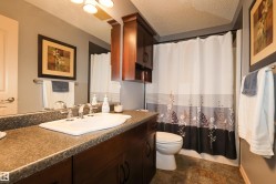Bathroom featuring a broad vanity with an integrated sink, dark wood-finish cabinetry, a full-width mirror, a shower with a shower curtain, and patterned floor tiling - 