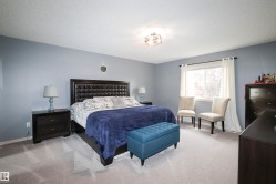 Expansive bedroom featuring light gray carpet flooring, a window with white drapes, and a decorative ceiling light fixture - 