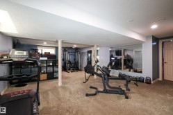 Finished lower level featuring recessed lighting, light gray walls, plush carpeting, a partial mirrored wall, and white trim - 