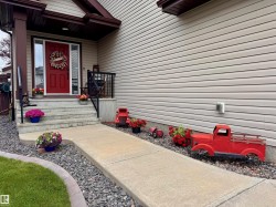 Red paneled front door with sidelight windows framed by a covered porch with black railings - 