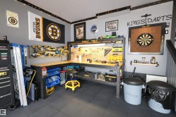 Dedicated workspace featuring a large L-shaped workbench with integrated lighting and pegboard storage - 