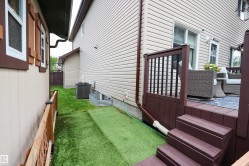 Rear exterior featuring a multi-level composite deck with steps and dark balusters, light-colored horizontal siding, and a window well - 