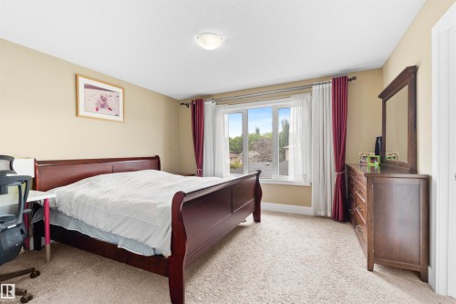 Carpeted bedroom with a large window, neutral wall tones, and crown molding - 11719 127 Street Nw, Edmonton, AB - Indoor Photo Showing Bedroom