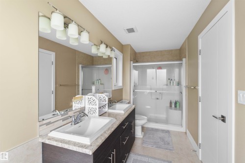 Bathroom featuring a dual vanity with dark wood-finish cabinetry, light-toned countertops, and two rectangular sinks - 11719 127 Street Nw, Edmonton, AB - Indoor Photo Showing Bathroom