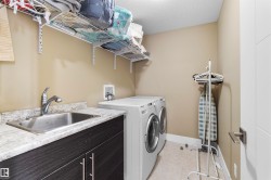 Dedicated laundry area featuring a stainless steel sink, wood-finish cabinetry, and a light-toned countertop - 