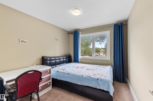 Carpeted bedroom featuring a large window, neutral wall paint, and a flush mount ceiling light - 11719 127 Street Nw, Edmonton, AB - Indoor Photo Showing Bedroom