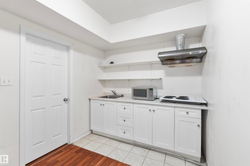 Compact kitchen area featuring white cabinetry, a single-basin sink, and a built-in range hood - 11719 127 Street Nw, Edmonton, AB - Indoor Photo Showing Kitchen