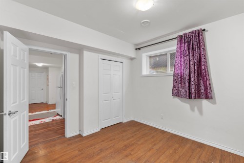 Room featuring wood-finish flooring, white painted walls, a flush-mount ceiling light, and a window with a curtain rod - 11719 127 Street Nw, Edmonton, AB - Indoor Photo Showing Other Room