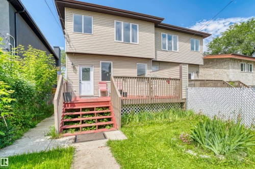 Rear exterior featuring horizontal vinyl siding, a multi-level wood deck, and multiple windows across two stories - 11719 127 Street Nw, Edmonton, AB - Outdoor With Deck Patio Veranda