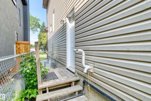 Siding exterior featuring a side entry door with adjacent outdoor lighting - 11719 127 Street Nw, Edmonton, AB - Outdoor