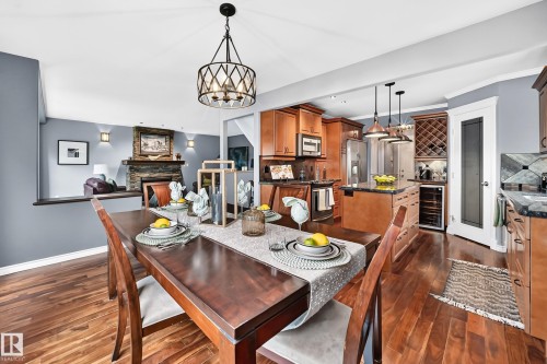 Warm wood-finish flooring extending from the dining area into the kitchen - 12720 Hudson Way Nw, Edmonton, AB - Indoor Photo Showing Dining Room