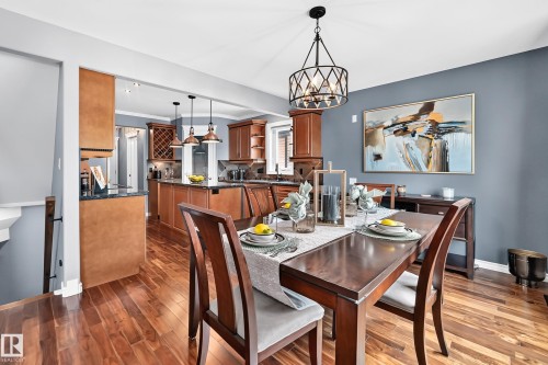 Formal dining area with wood-finish flooring, a contemporary chandelier, and a feature wall - 12720 Hudson Way Nw, Edmonton, AB - Indoor Photo Showing Dining Room