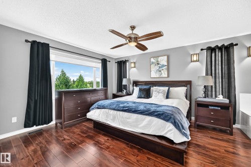 Spacious bedroom featuring wood-finish flooring, a ceiling fan, and recessed wall sconces - 12720 Hudson Way Nw, Edmonton, AB - Indoor Photo Showing Bedroom