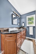 Spacious vanity area featuring rich wood cabinetry with black hardware, a dark countertop, and a tiled backsplash - 